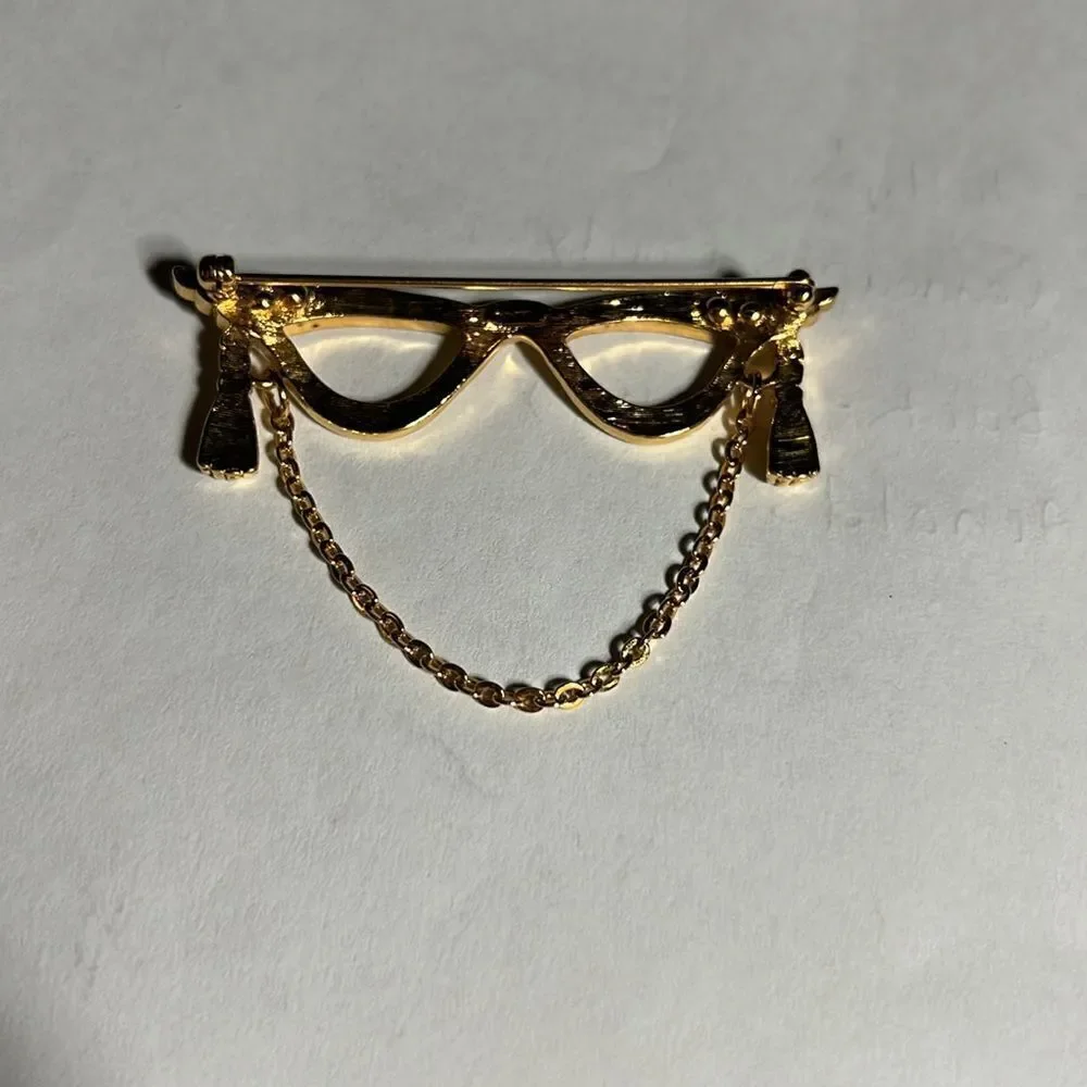 Avon golden eyeglass holder brooch with gold tassel.